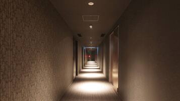 A long, narrow hallway with carpeted floors and walls, illuminated by overhead lights.