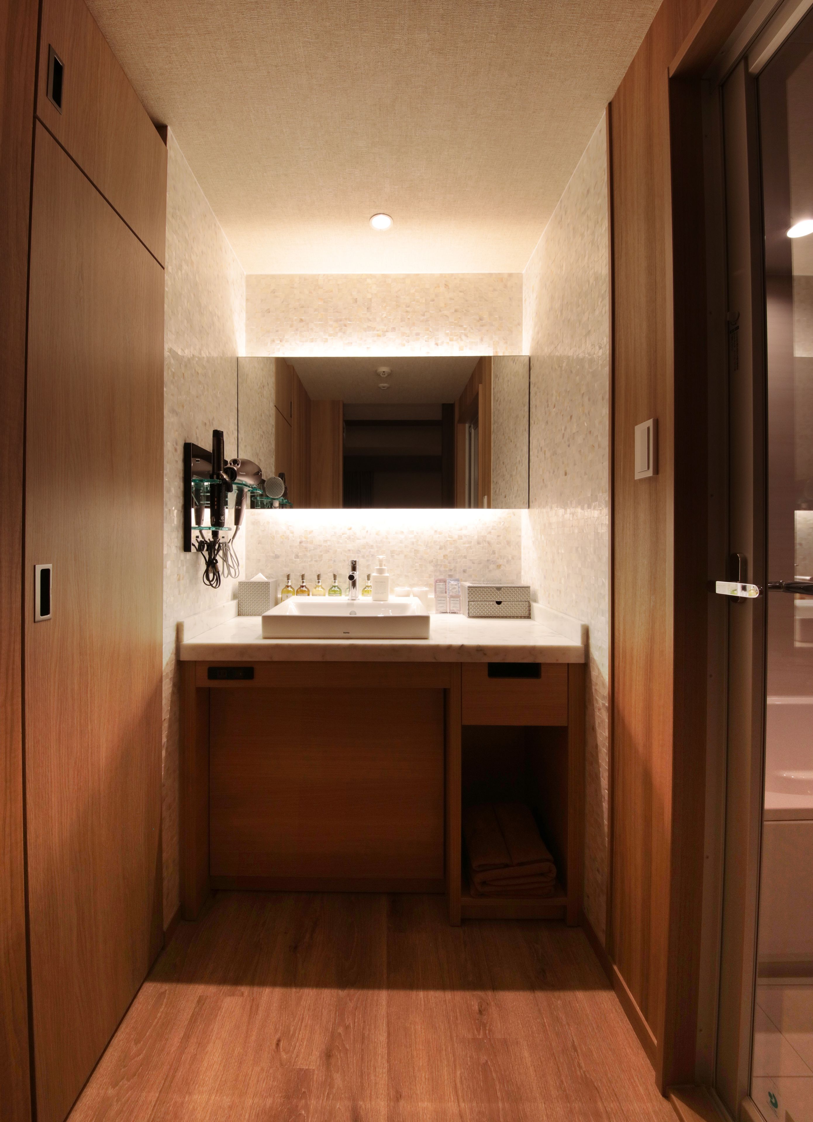 A modern bathroom with a wooden vanity, a sink, and a mirror.