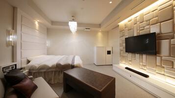 Una habitación de hotel moderna con una cama grande, un televisor montado en una pared texturizada, un escritorio pequeño y un sofá.