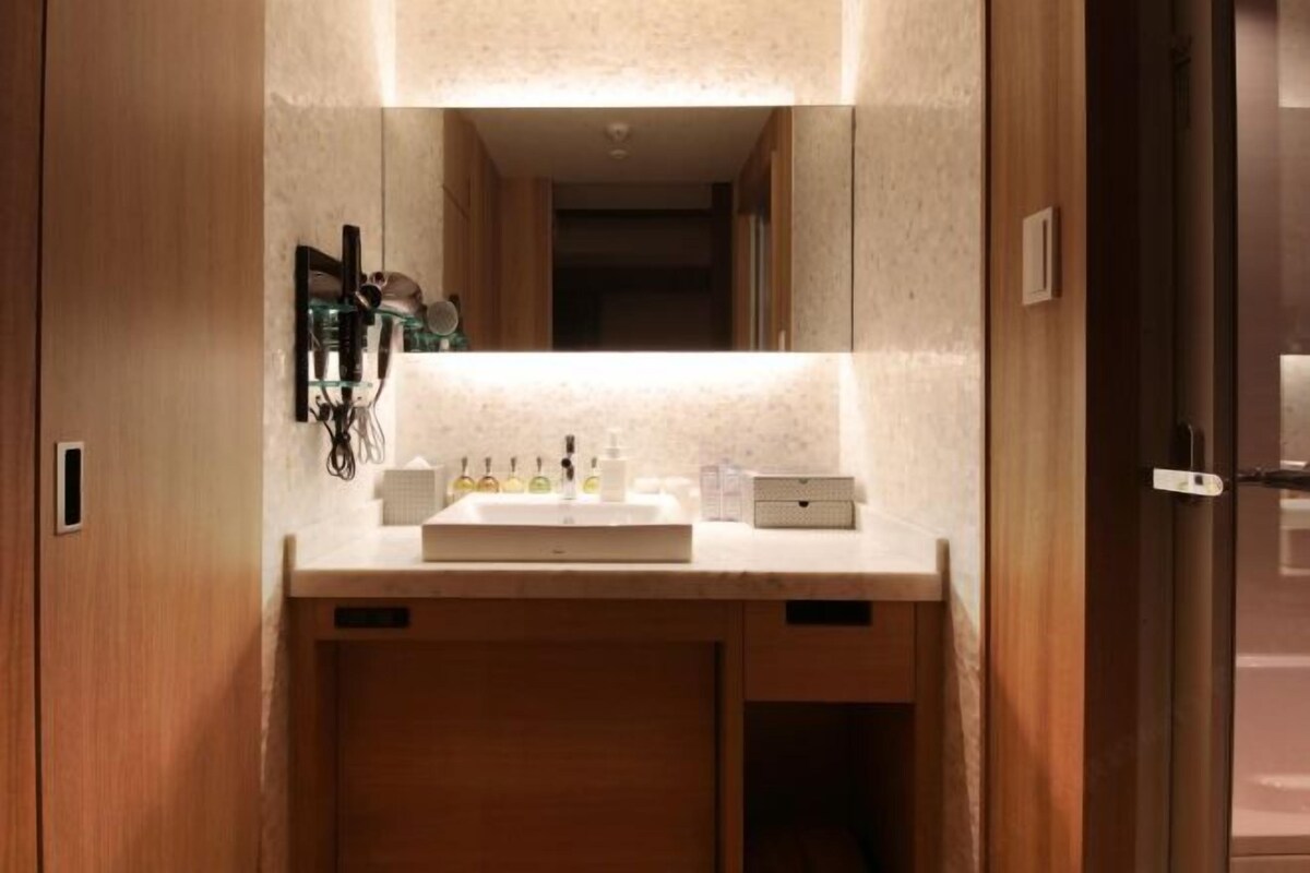 A bathroom with a sink, mirror, and toiletries.