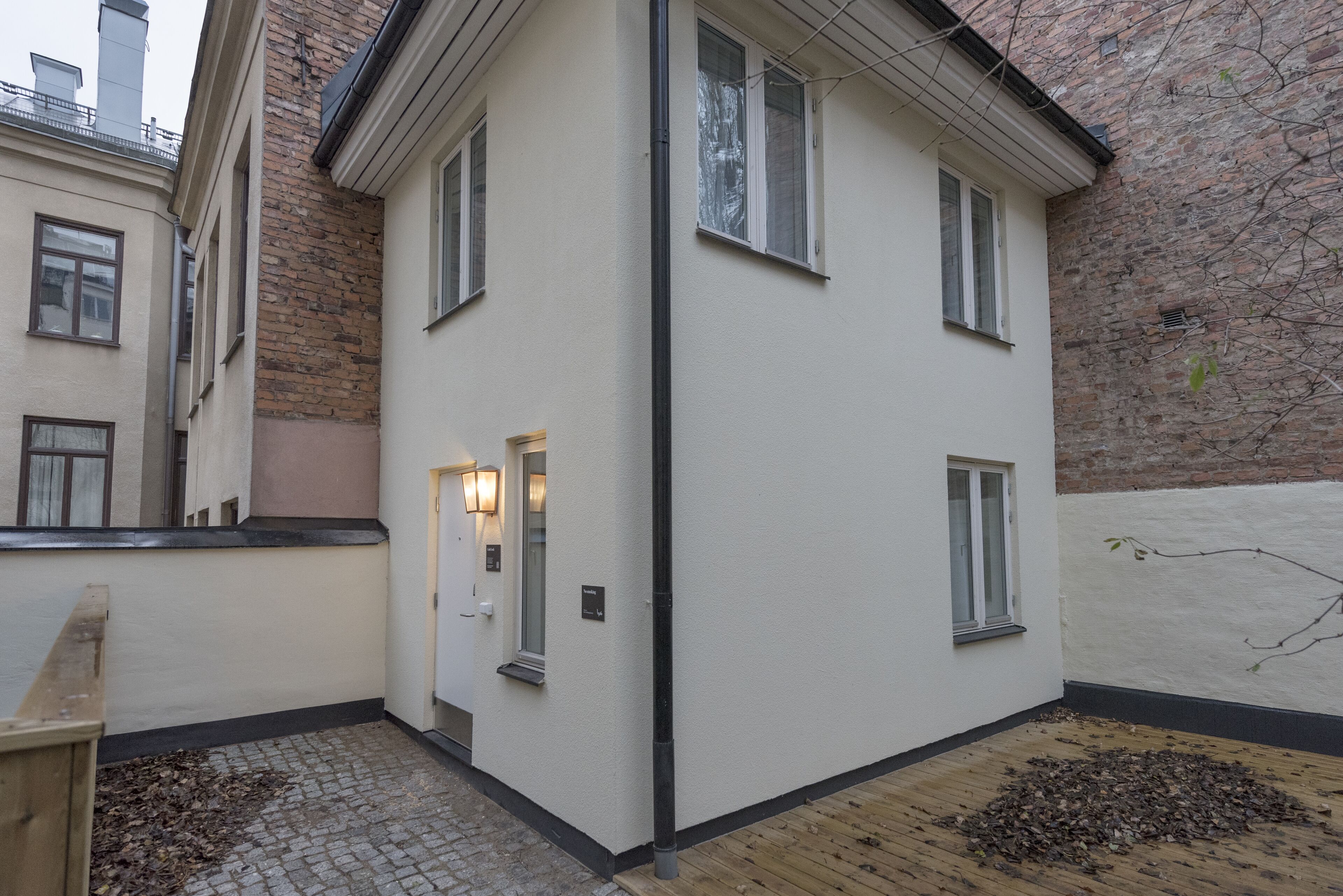 A corner building with a white facade, a black gutter, and a cobblestone path.