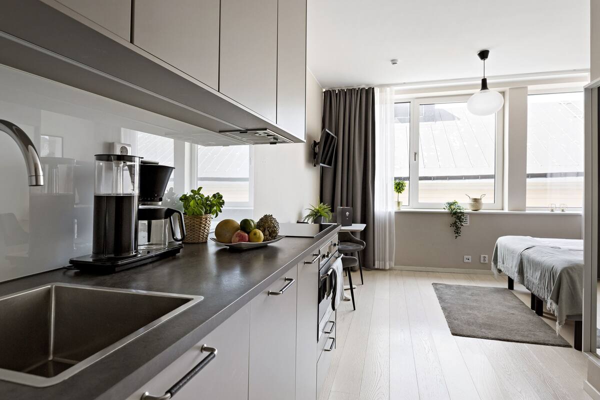 Cozinha moderna com uma ilha grande, eletrodomésticos embutidos e vista para a sala de estar.
