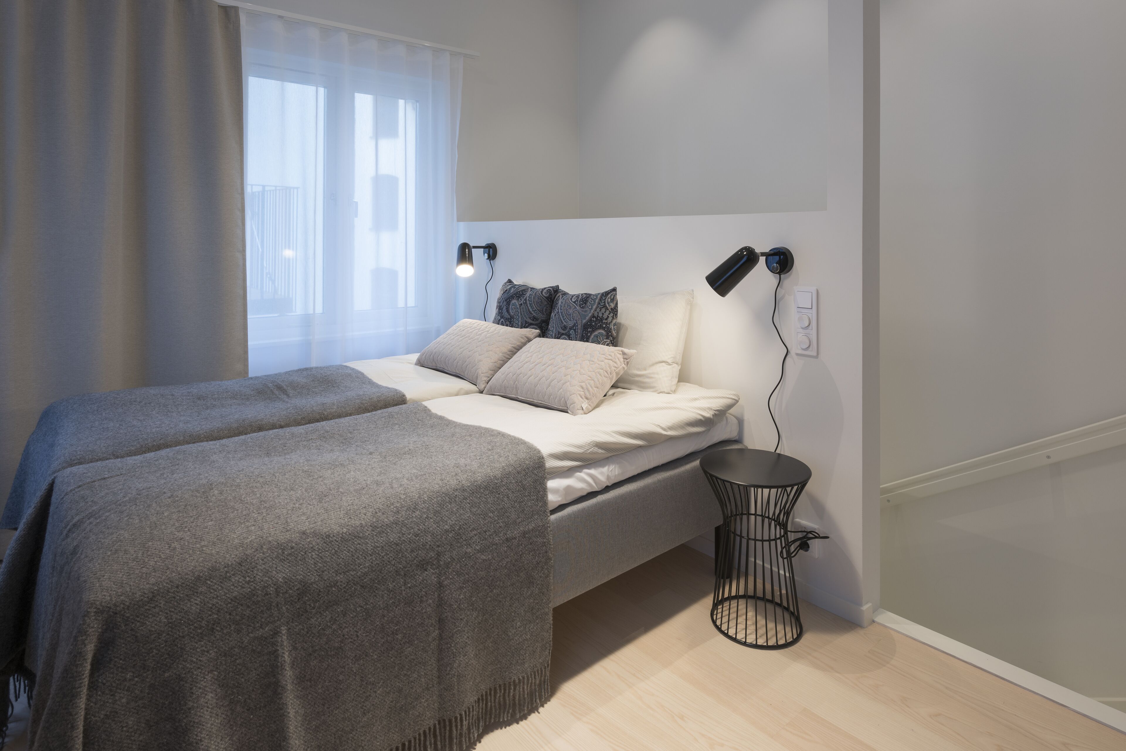 Ein modernes Schlafzimmer mit einem Bett, Nachttischlampen und einem kleinen runden Tisch.