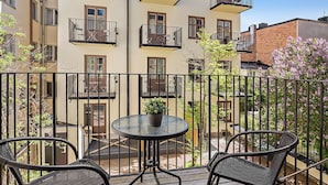 A balcony with a round table and two chairs, surrounded by a metal railing. - Forenom Apartments Stockholm Johannesgatan (Stockholm)