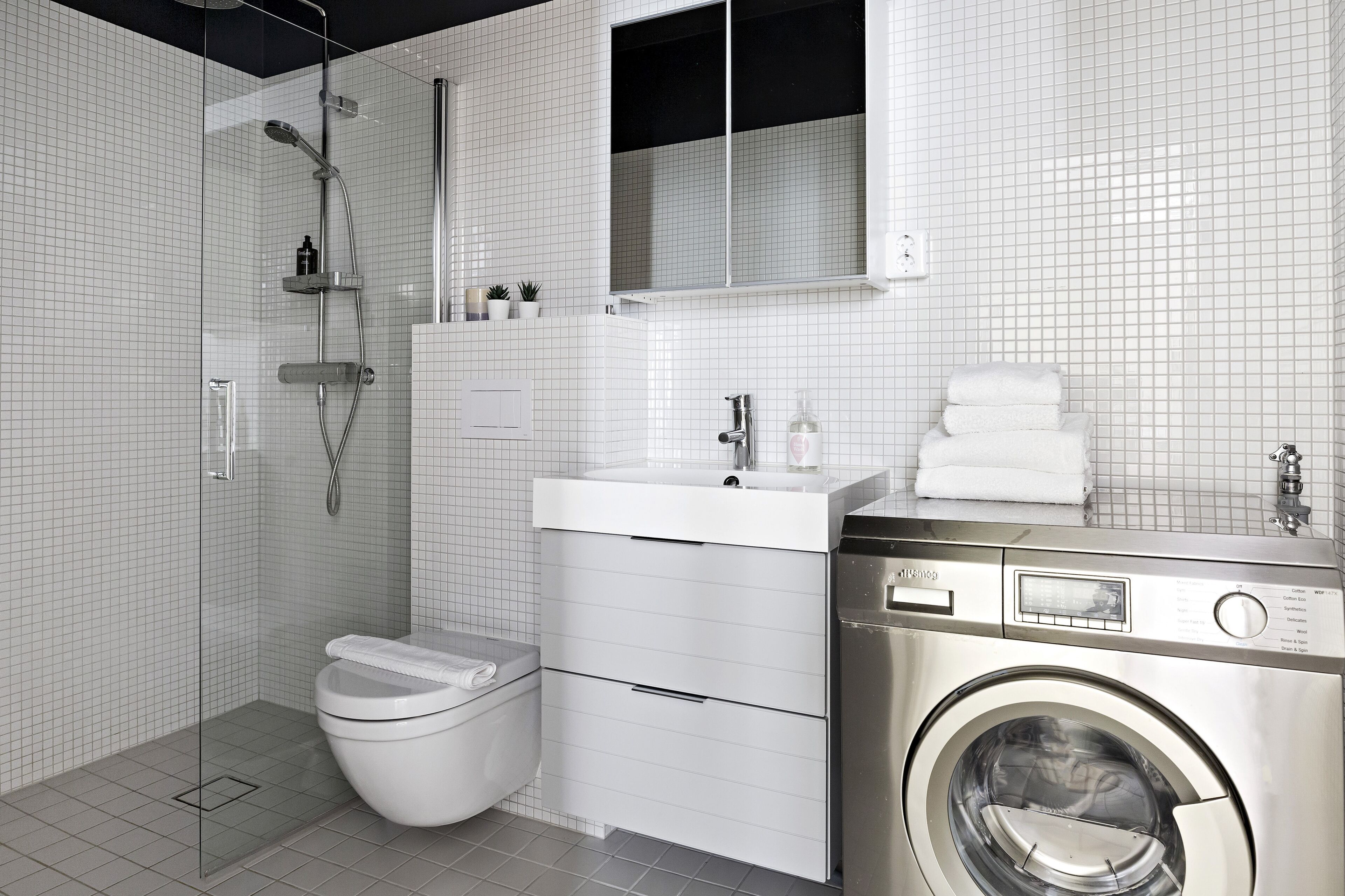 Un baño moderno con inodoro, lavamanos y lavadora integrada.