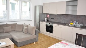 A modern kitchen with a built-in oven, a sink, and a dining area with a table and a sofa. - Ebersheim Luxus Plaza (Mainz)