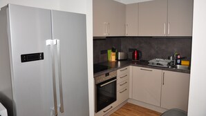 A compact kitchen with a stainless steel refrigerator, a built-in oven, and a sink. - Ebersheim Luxus Plaza (Mainz)
