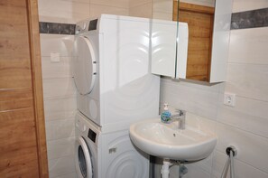 A compact bathroom with a washing machine, a sink, and a mirror. - Ebersheim Luxus Plaza (Mainz)