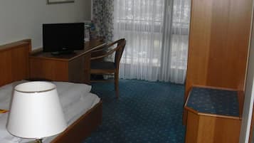 Une chambre d’hôtel équipée d’un lit, d’un bureau, d’une télévision, d’une lampe, d’un téléphone et d’une armoire.