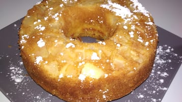 Ein runder, goldbrauner Kuchen mit Puderzucker auf einem Teller.