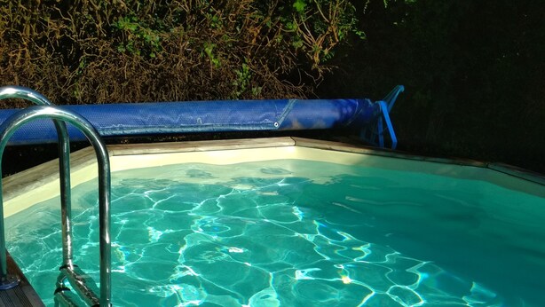 Een zwembad met helder water en een houten terras.