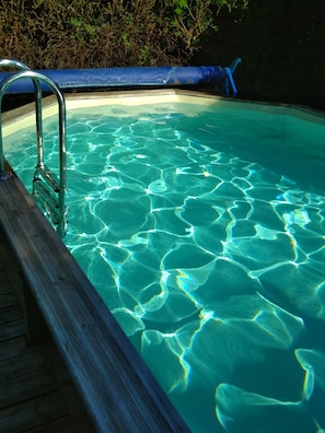 Una piscina con agua cristalina y un muelle de madera.