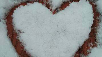 Un motif en forme de cœur réalisé dans la neige sur une surface en briques.