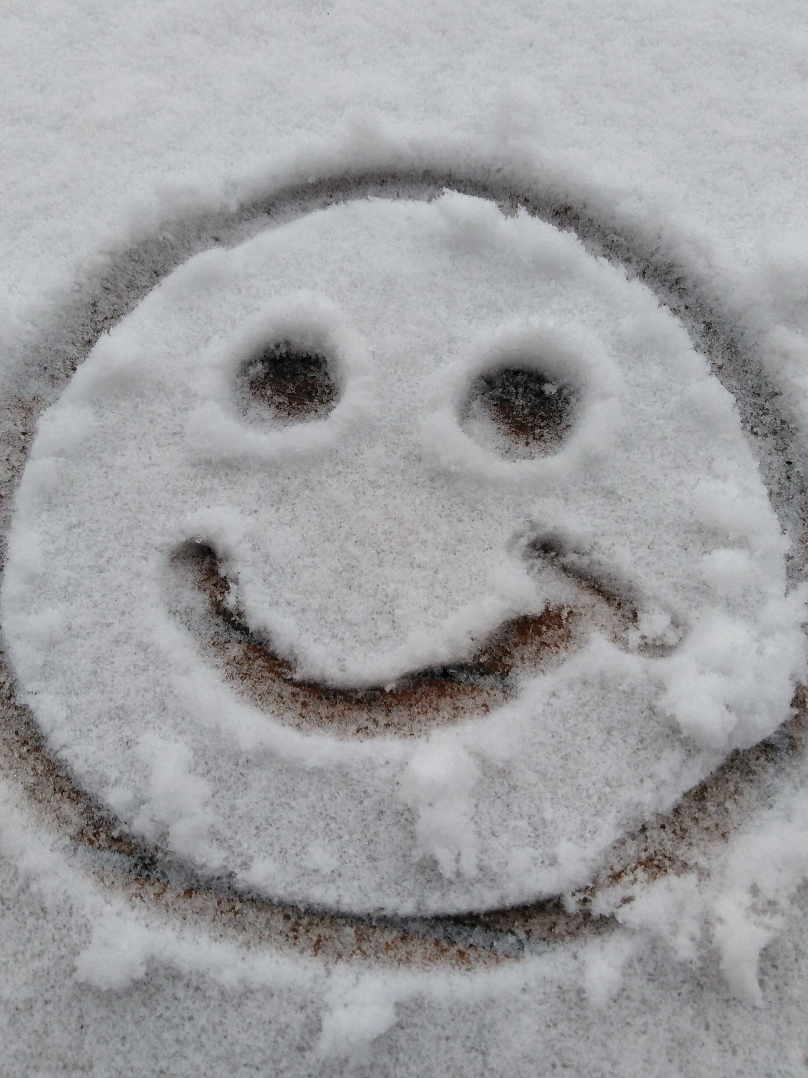Un suelo cubierto de nieve con un rostro sonriente dibujado en ella.