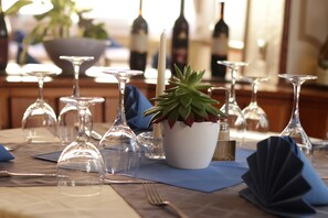 A dining table set with wine glasses, a candle, and a potted plant.