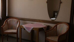 A room with two wooden chairs, a small table with a pink tablecloth, and a mirror on the wall. - Hotel-Ristorante Ätna (Ulrichstein)