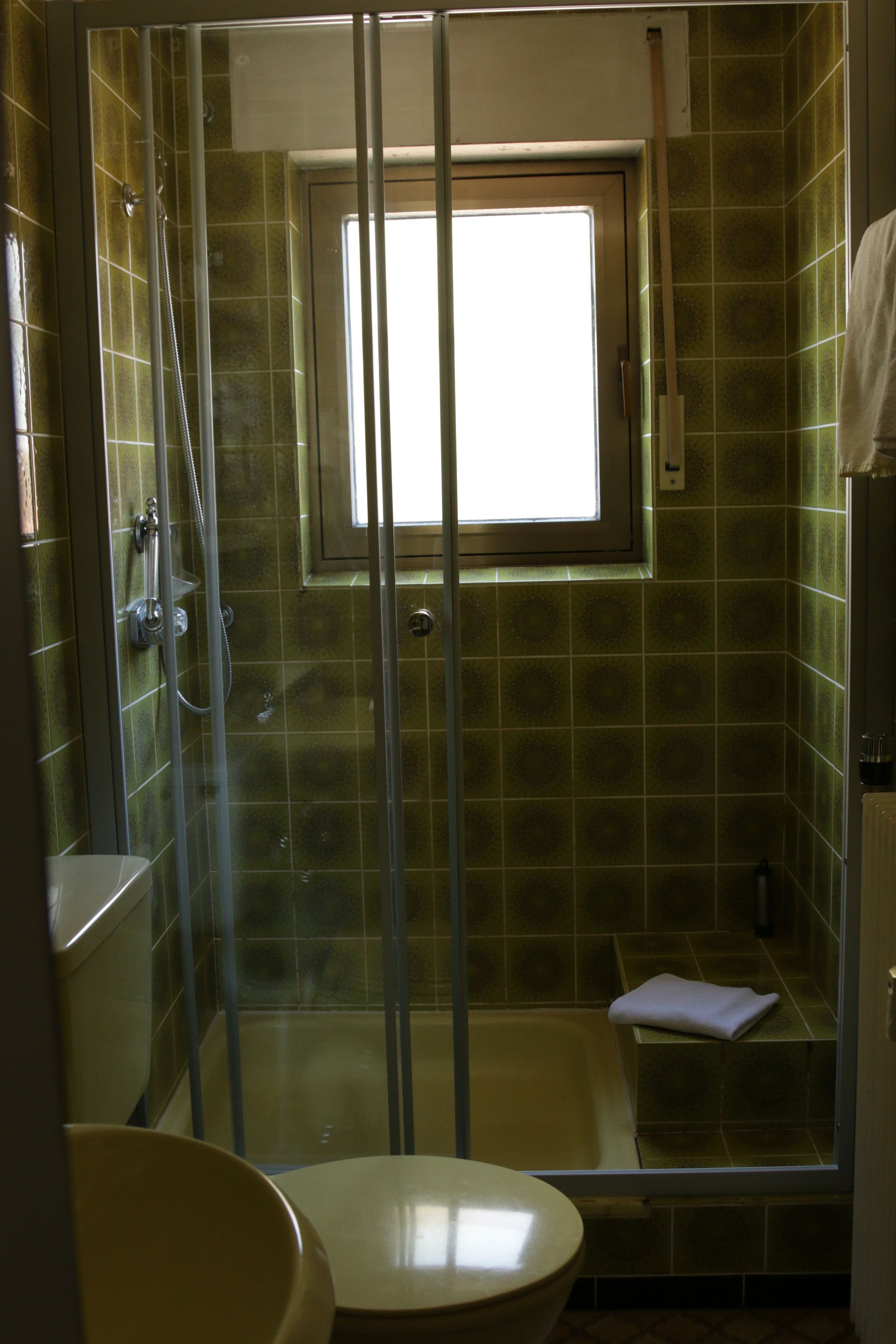 Een badkamer met een glazen douchecabine, toilet en bad.