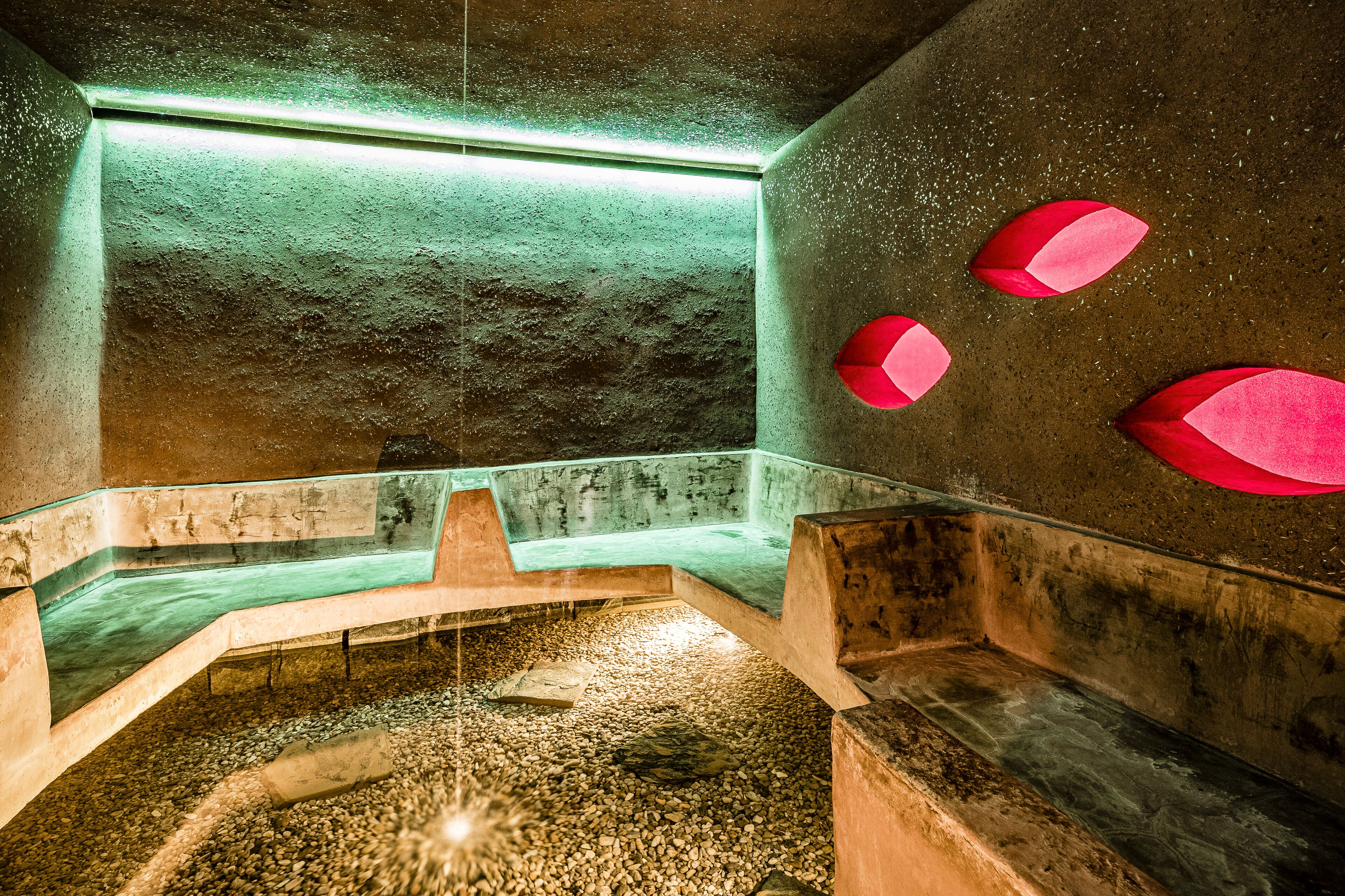 Uma área de spa com parede de pedra, um banco de vidro e um recurso de água.