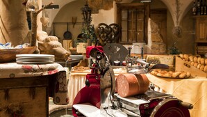 Uma cozinha rústica com um fatiador de carne, móveis de madeira e paredes de pedra.