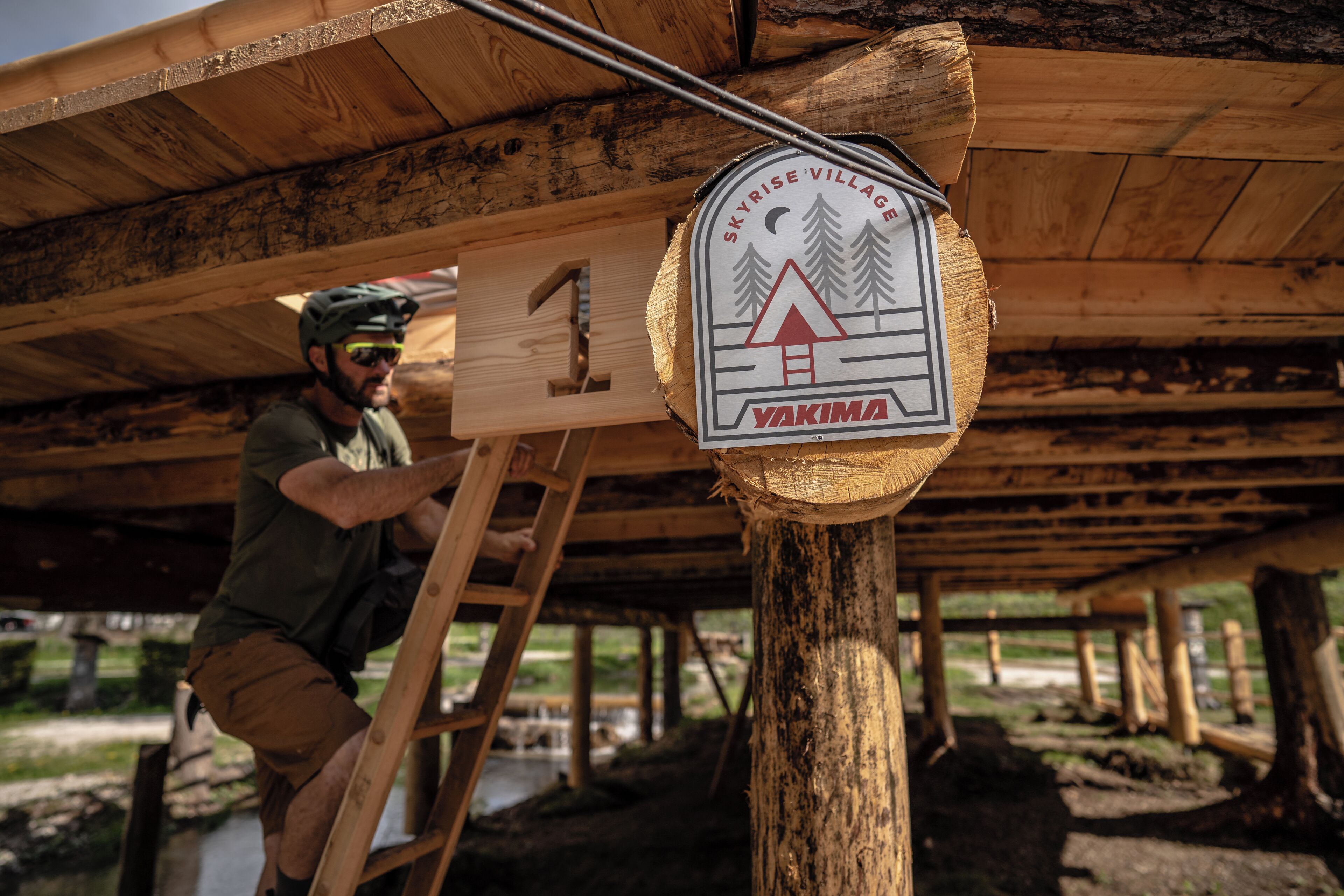 Une personne qui vise une cible, avec une structure en bois en arrière-plan.