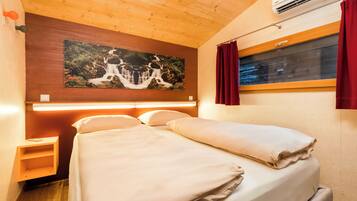 Une chambre à coucher avec un lit, une table de chevet, un climatiseur fixé au mur, une fenêtre avec des rideaux et un tableau au-dessus du lit.