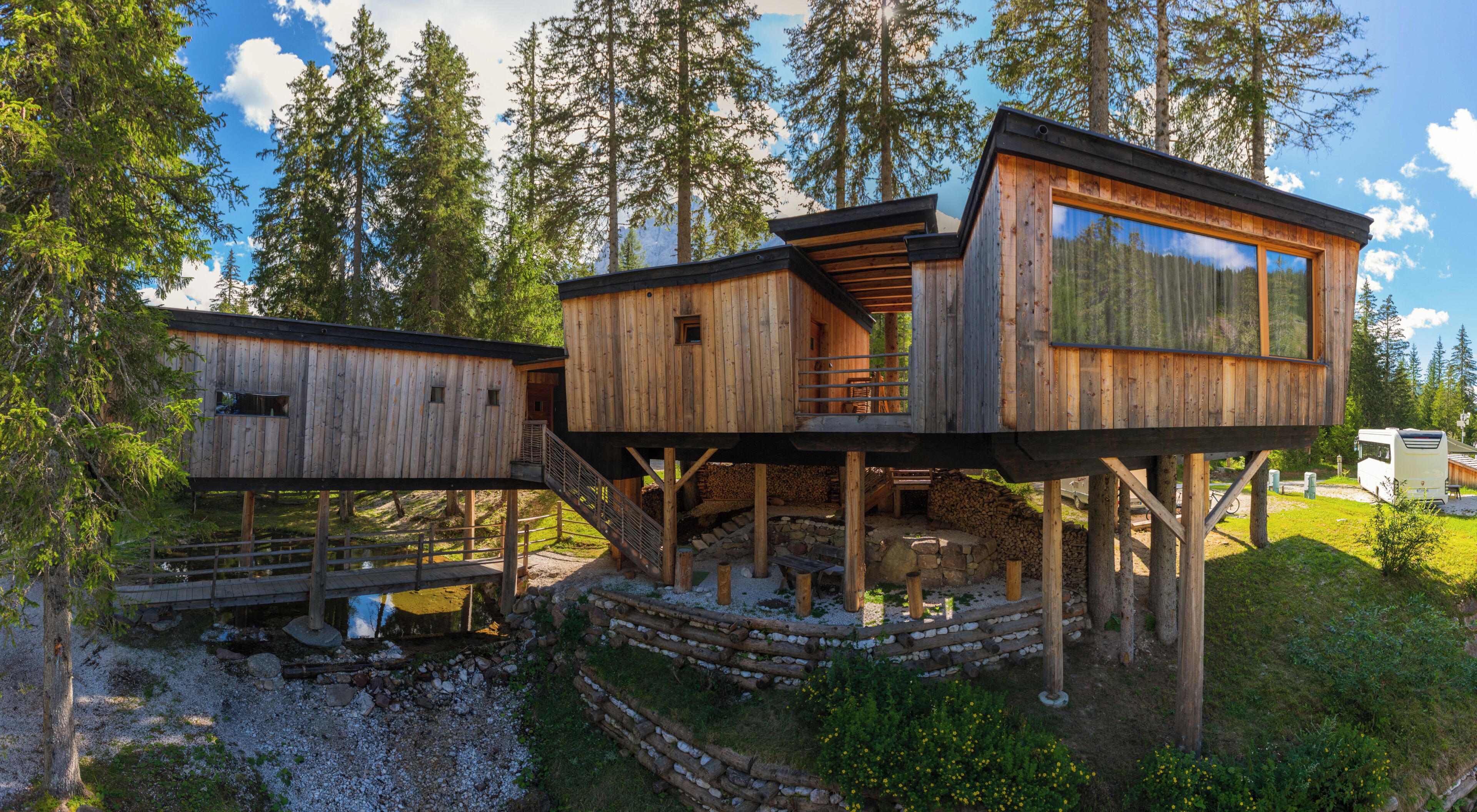 Eine Holzhütte mit Balkon und Treppe, umgeben von Bäumen.