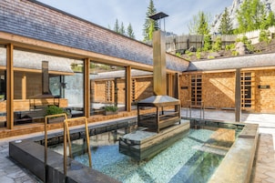 Un edificio moderno con ventanas amplias, una piscina y una terraza de madera.