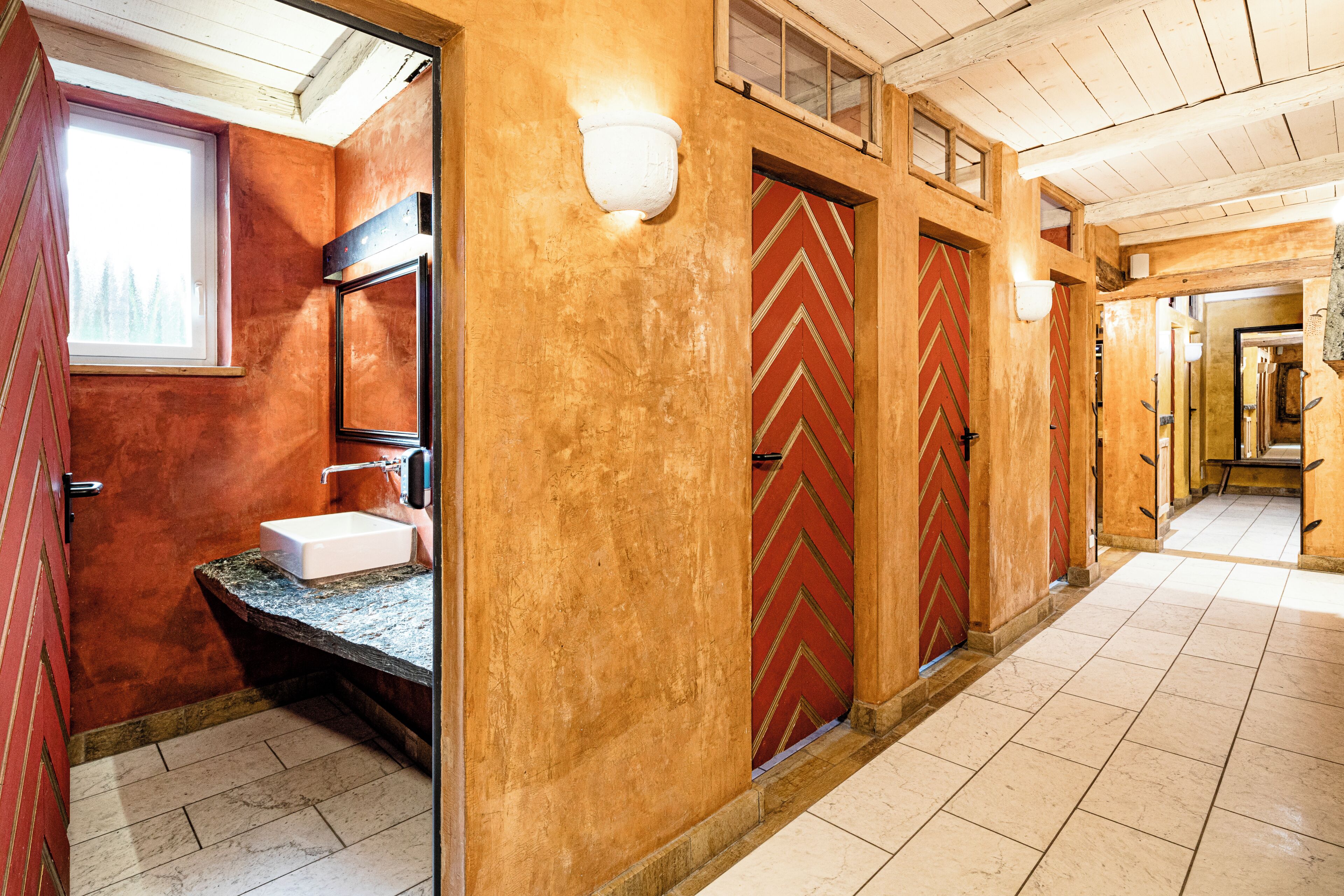 A corridor with a sink, a mirror, and a window.