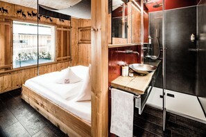 Una habitación de madera con cama, lavamanos y ducha.