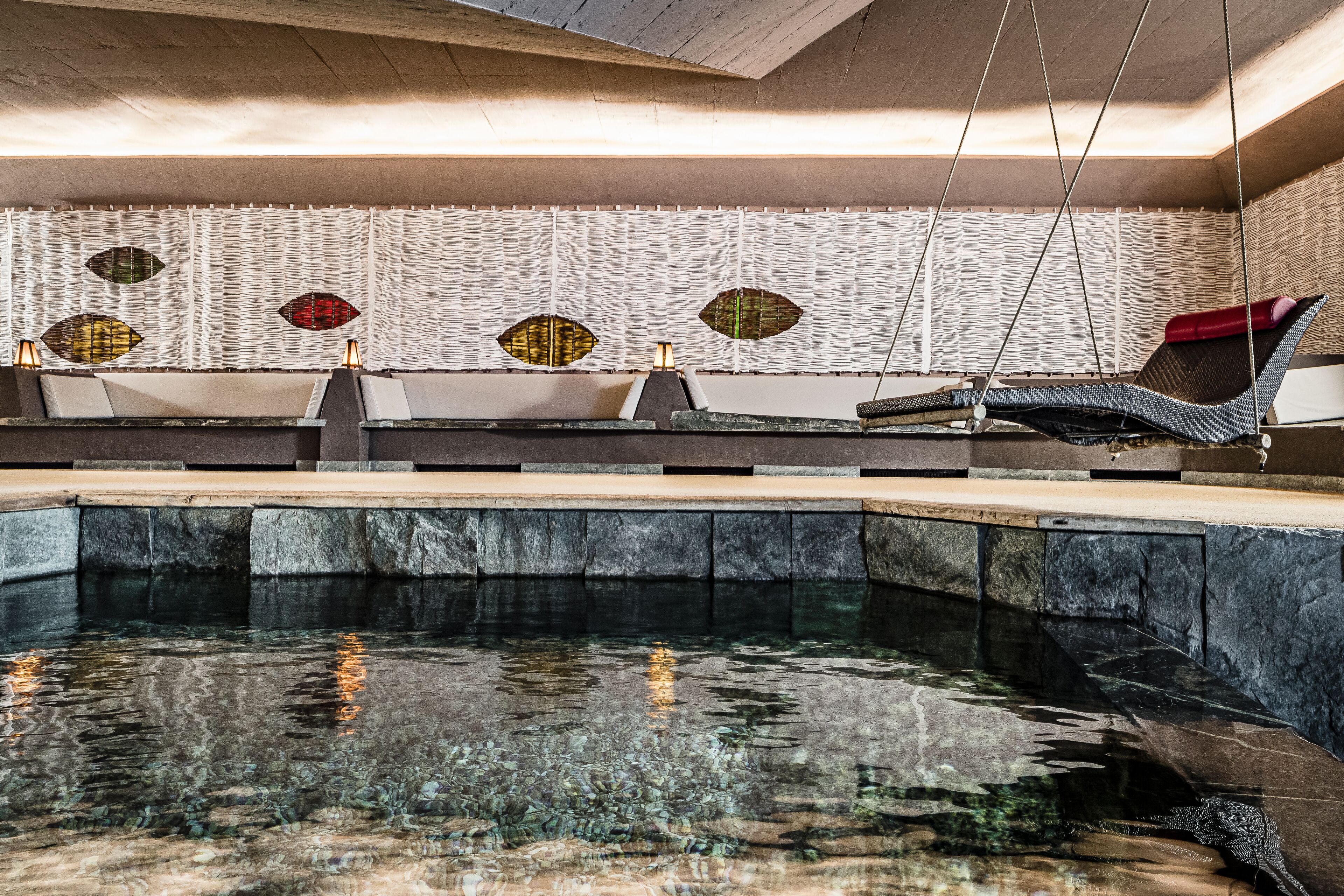 Un espace spa comprenant une piscine, des chaises longues et un mur orné de panneaux décoratifs.