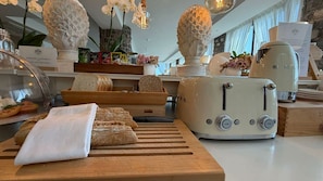 A kitchen with a vintage toaster, a cutting board with bread, and a variety of kitchen items.
