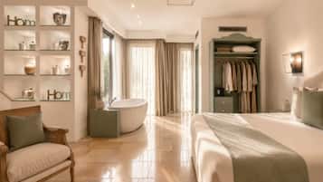 Quarto de hotel com cama, uma cadeira, toucador com espelho, banheira e guarda-roupa.