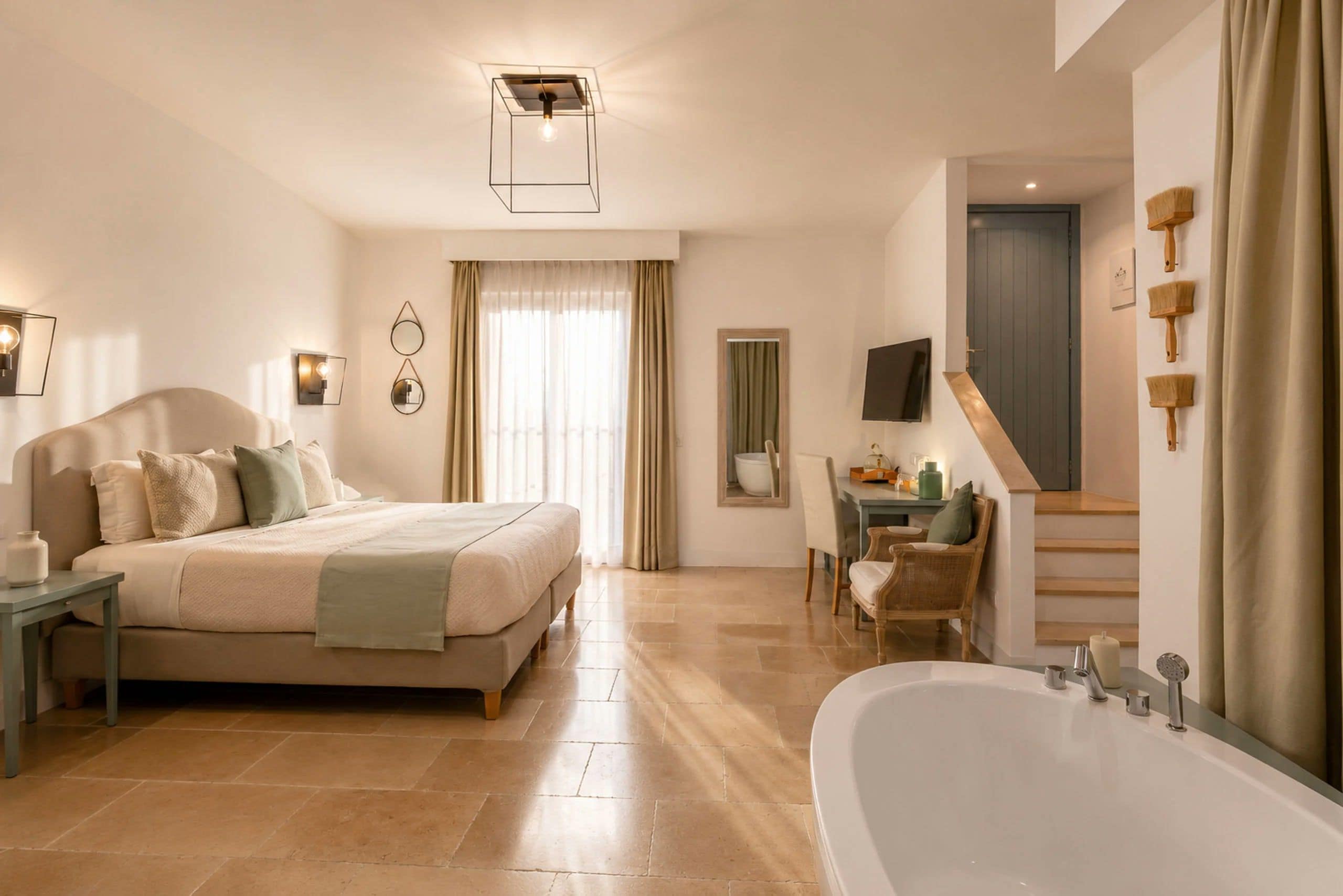 Un dormitorio moderno con una cama grande, un escritorio, una silla, un televisor y un baño con bañera.