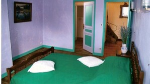 Una habitación con dos camas, un cuadro en la pared y una escalera que lleva a otra estancia.