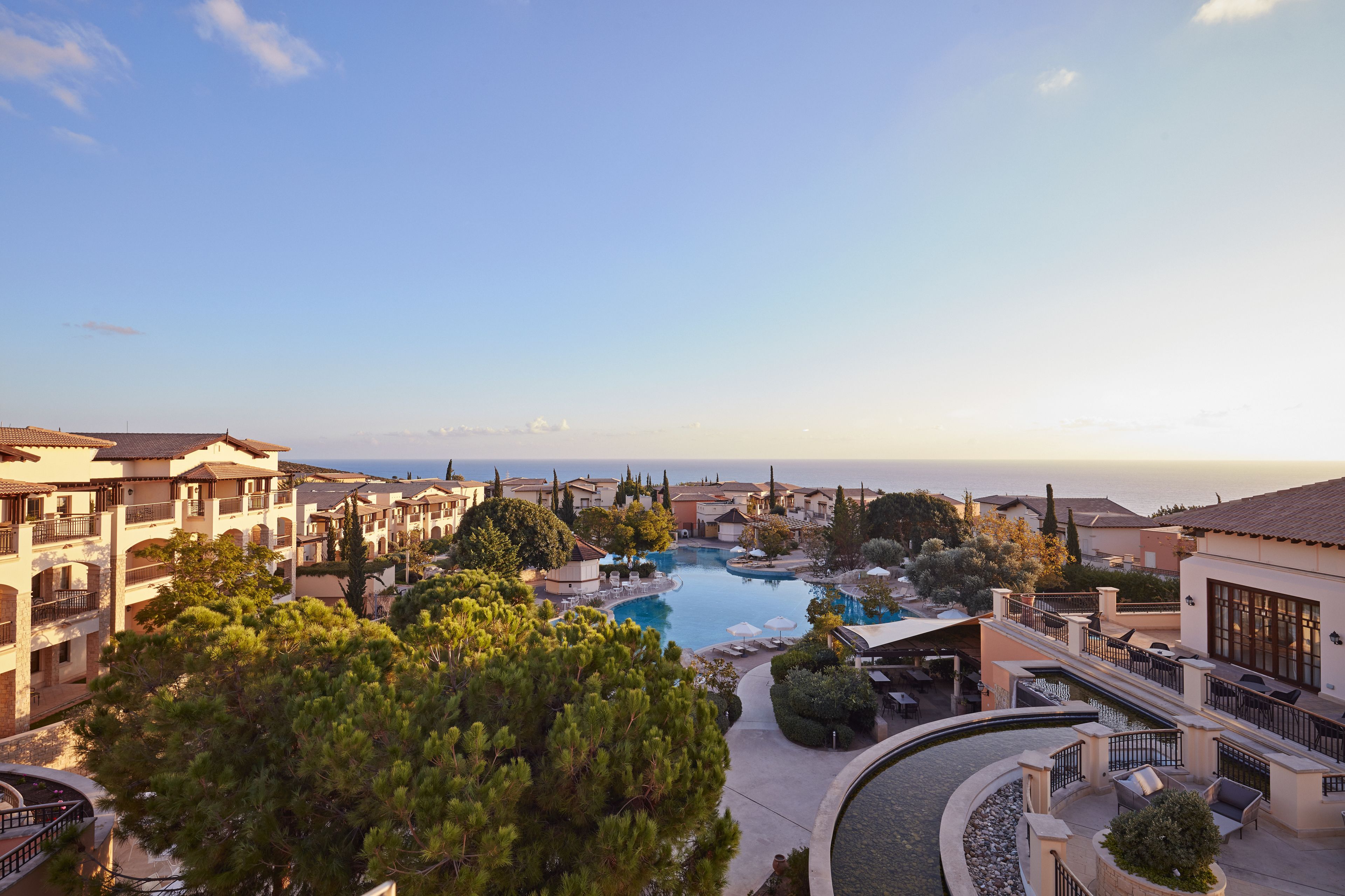 A resort with multiple swimming pools, outdoor seating areas, and a view of the sea.