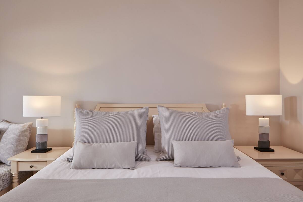 A neatly made bed with two pillows and two bedside tables with lamps.
