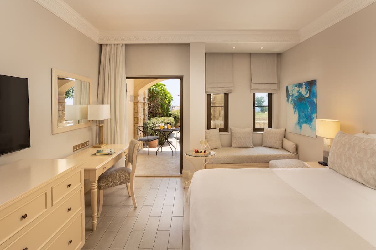 A hotel room with a bed, a desk, a chair, a TV, and a painting.