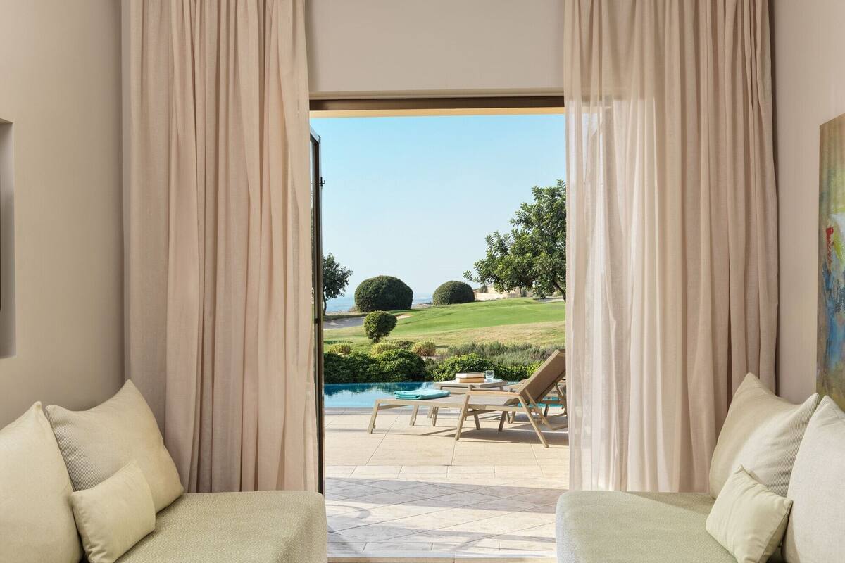 A room with two sofas facing a pool and a golf course view.