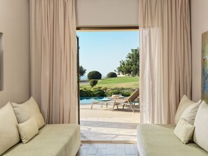 Quarto com dois sofás de frente para uma piscina e vista para um campo de golfe.