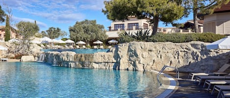 Una piscina cubierta, una piscina al aire libre, sombrillas, tumbonas