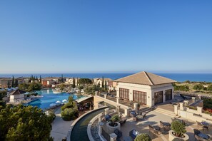 Un resort con una piscina amplia, mobiliario exterior y vista al mar.