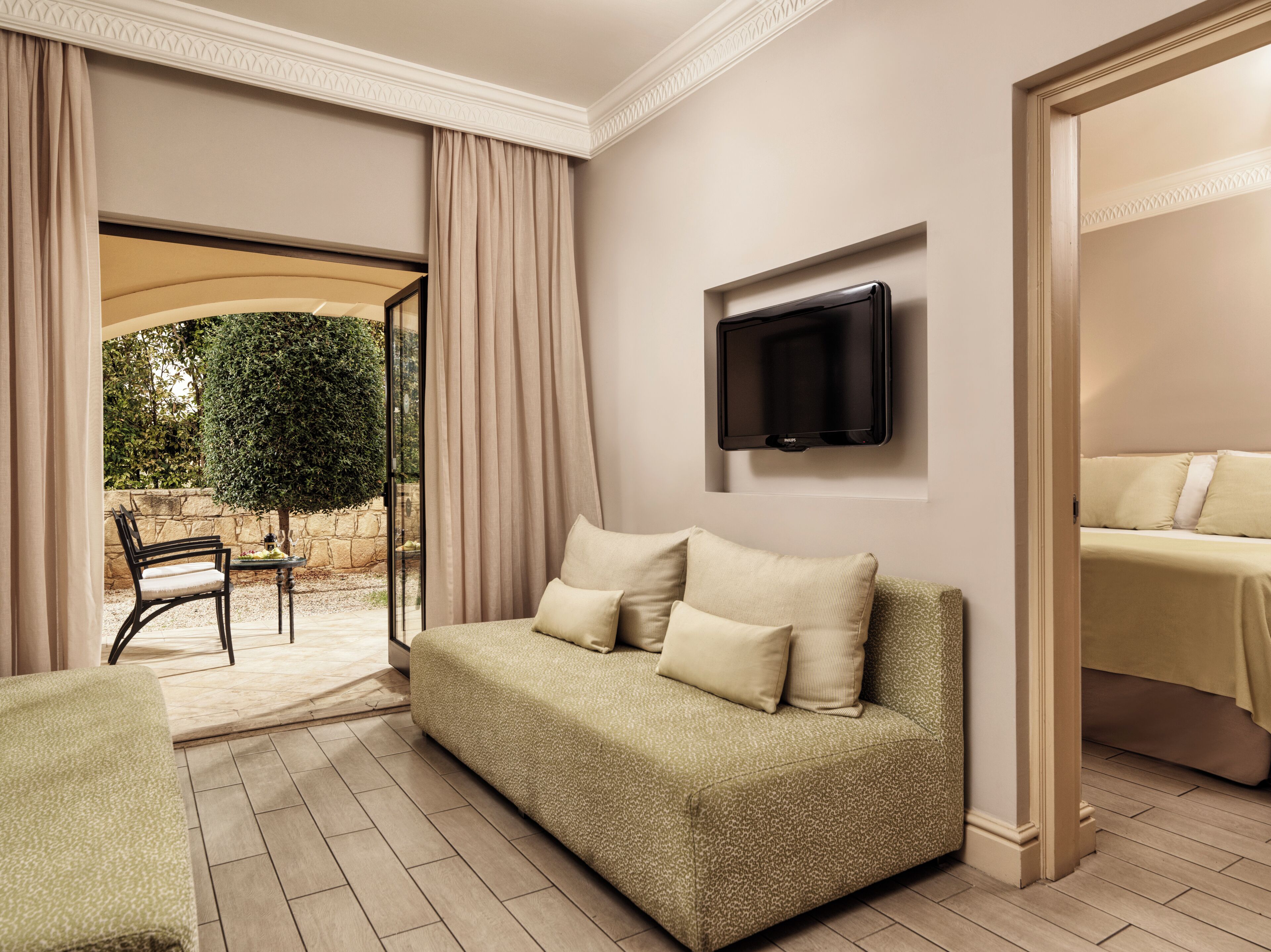 Un salon moderne avec un canapé, un téléviseur à écran plat et une vue sur un jardin.