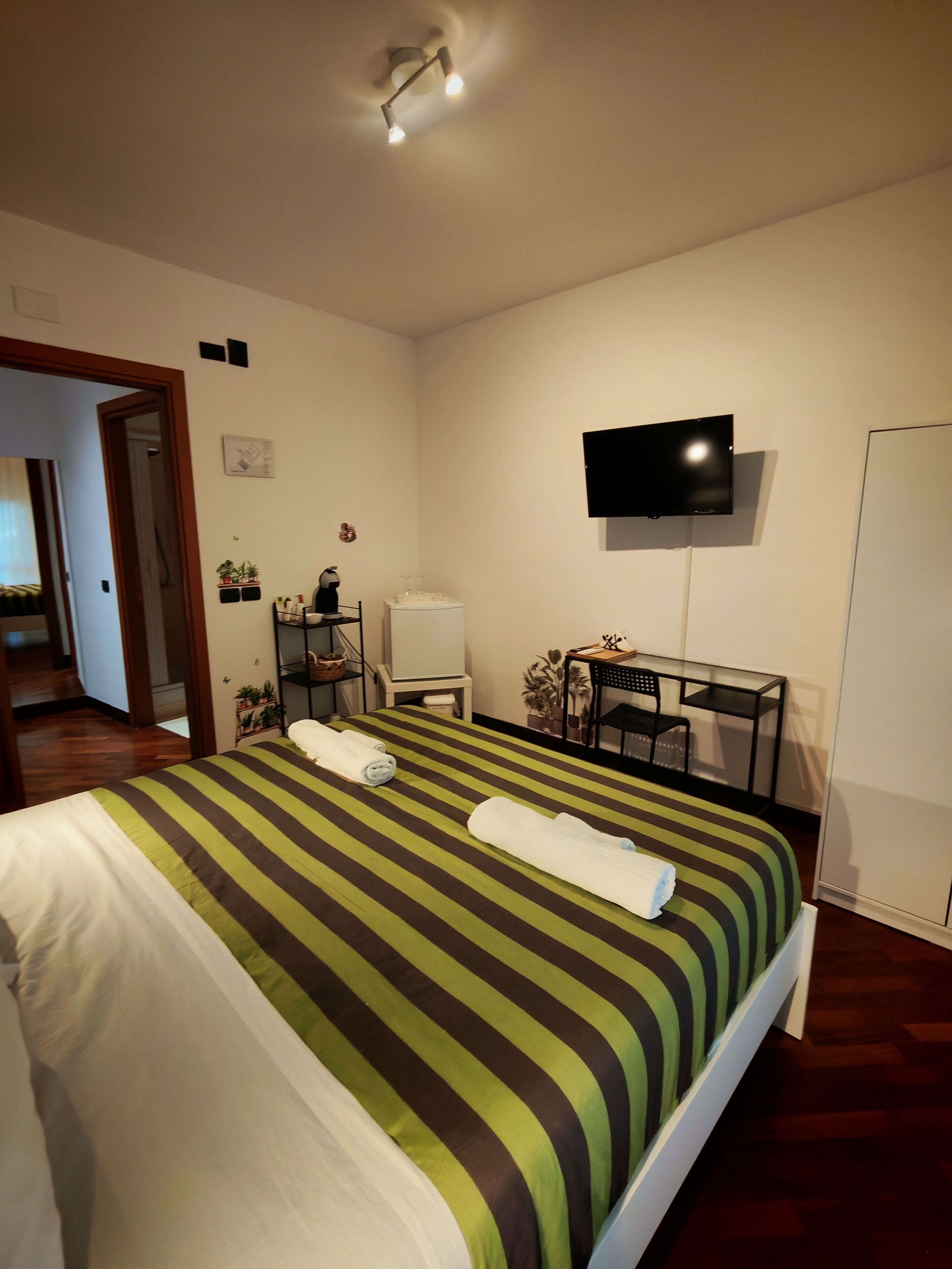 Hotellihuone, jossa on sänky, työpöytä, tuoli, televisio ja vaatekaappi.