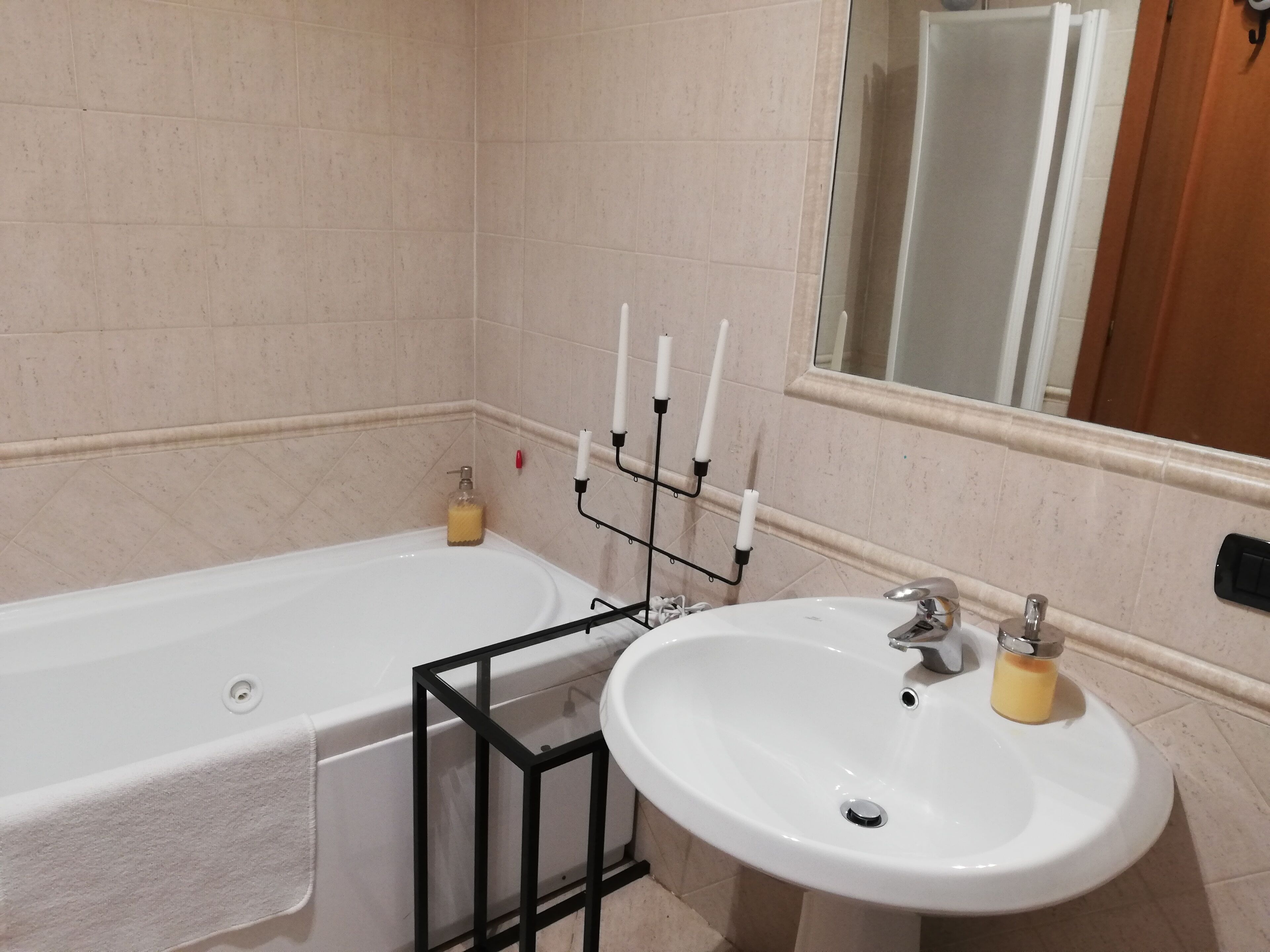A bathroom with a bathtub, a sink, and a mirror.