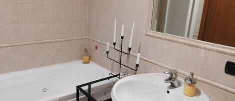 A bathroom with a bathtub, a sink, and a mirror.