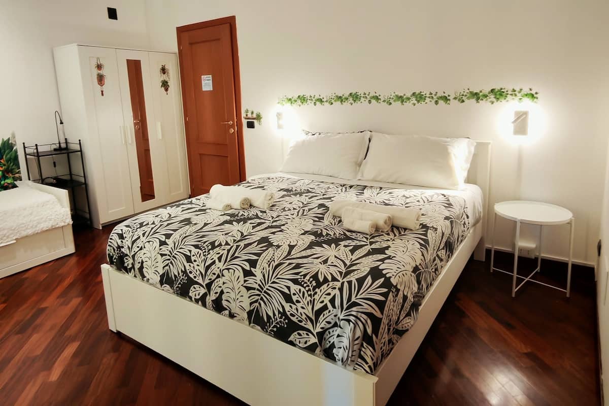 A bedroom with a bed, a wardrobe, a bedside table, and a small round table.