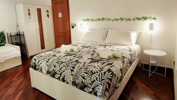 A bedroom with a bed, a wardrobe, a bedside table, and a small round table.