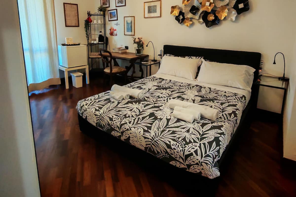 A neatly arranged bedroom with a large bed, a desk, and a chandelier.