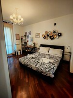 Un dormitorio ordenado con una cama grande, un escritorio y una araña.