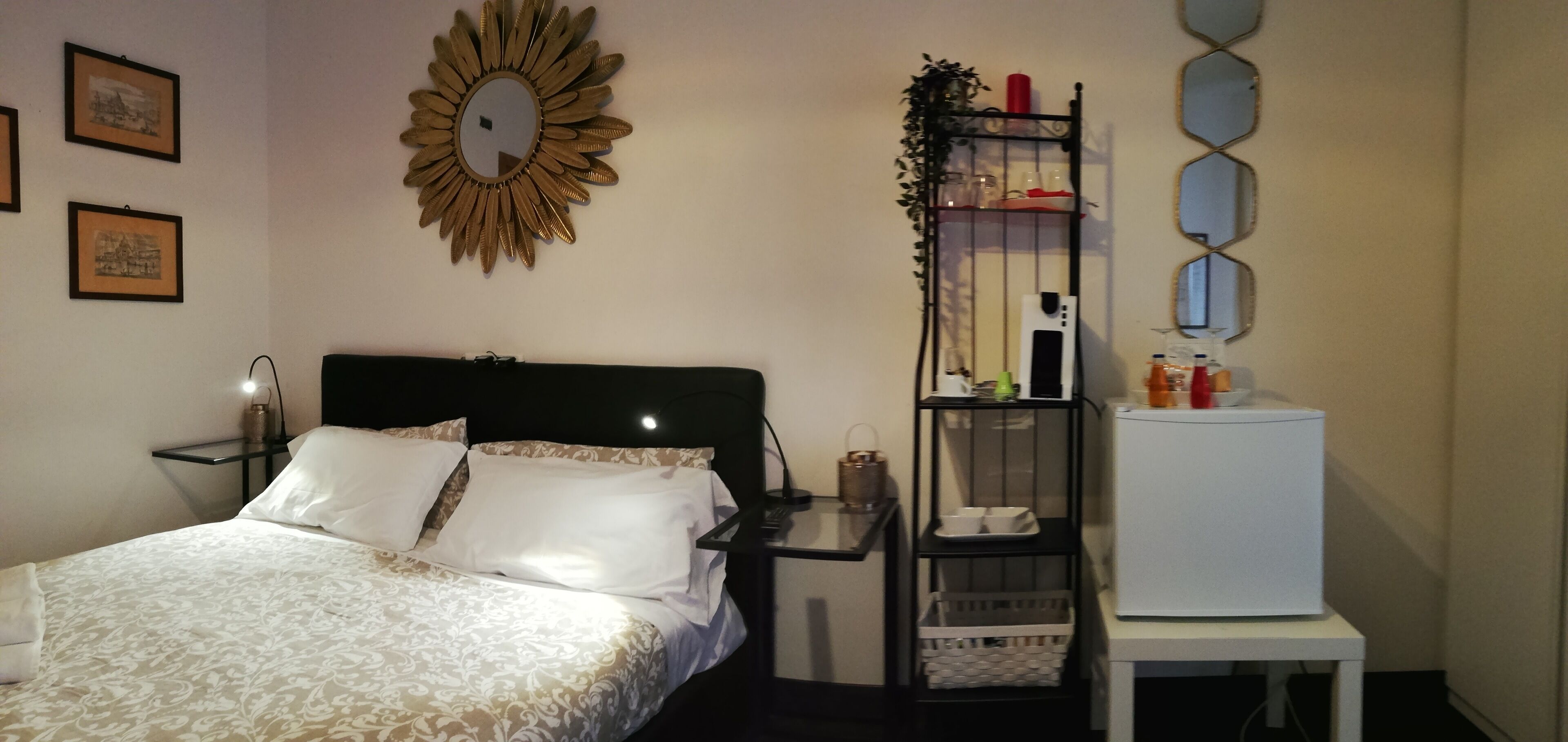 A neatly arranged hotel room with a bed, bedside table, nightstand, and a small white cabinet.